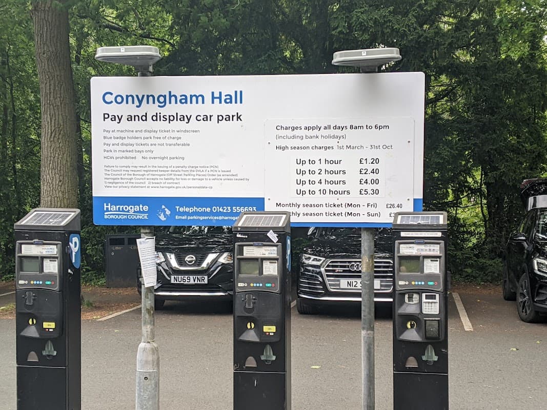 Sign for Conyngham Hall pay and display car park with pricing details; parked cars visible in the background.