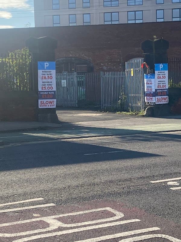 Entrance to Marsh Lane Car Park with signage displaying parking rates and instructions, flanked by brick pillars.