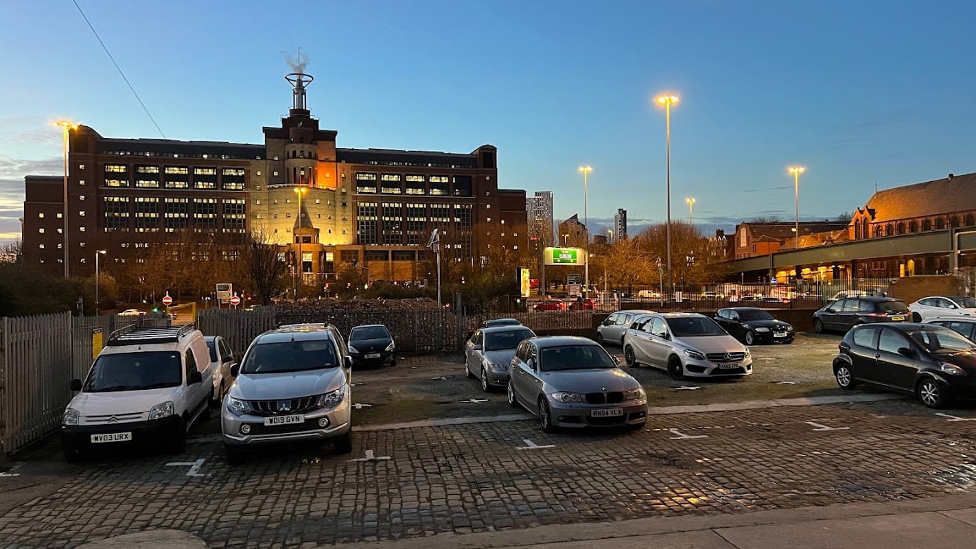 Shannon Street Car Park with parked cars, illuminated buildings, and a twilight sky in Knowsthorpe, Yorkshire.