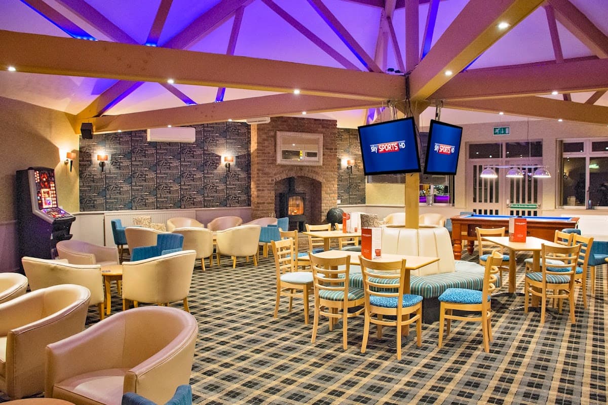 Cozy restaurant interior with wooden beams, seating areas, TVs, and a fireplace in Lebberston, Yorkshire.