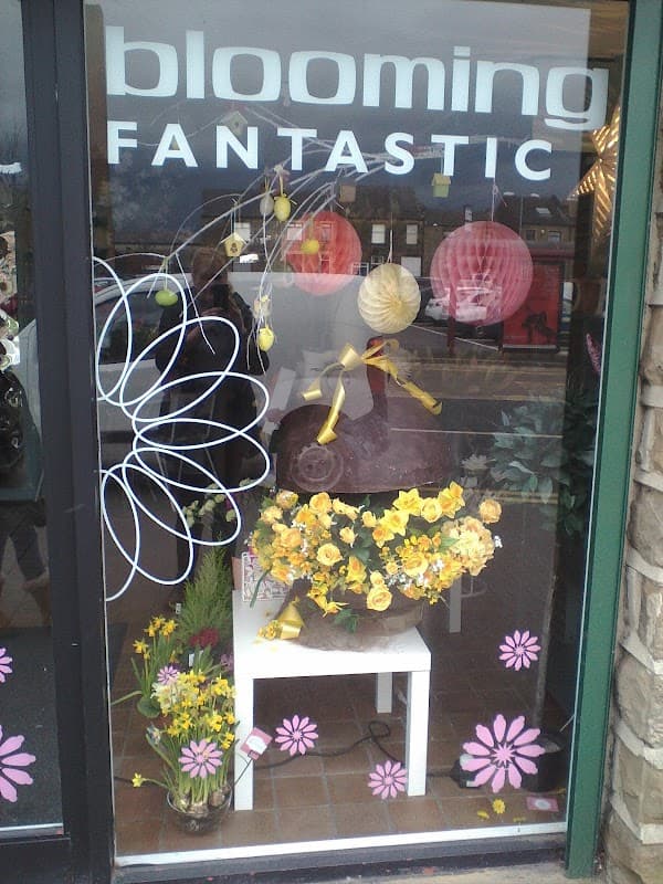 Colorful flower arrangements in a shop window, with decorative paper lanterns and cheerful floral designs.
