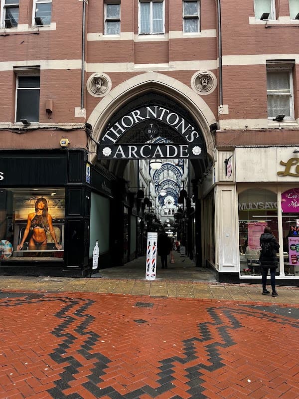 Entrance to Thornton's Arcade with shops on either side and a patterned brick pathway.