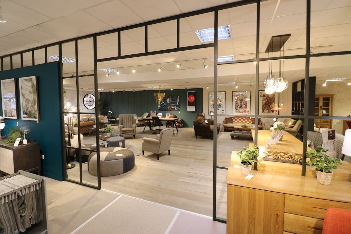 Modern furniture showroom featuring stylish seating, decorative plants, and art pieces in a spacious layout.
