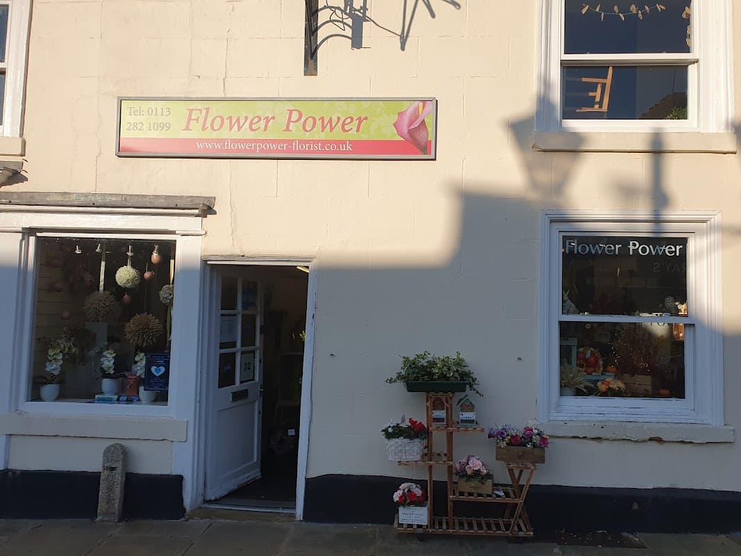Brightly colored flower shop exterior with a sign reading "Flower Power" and floral displays in windows.