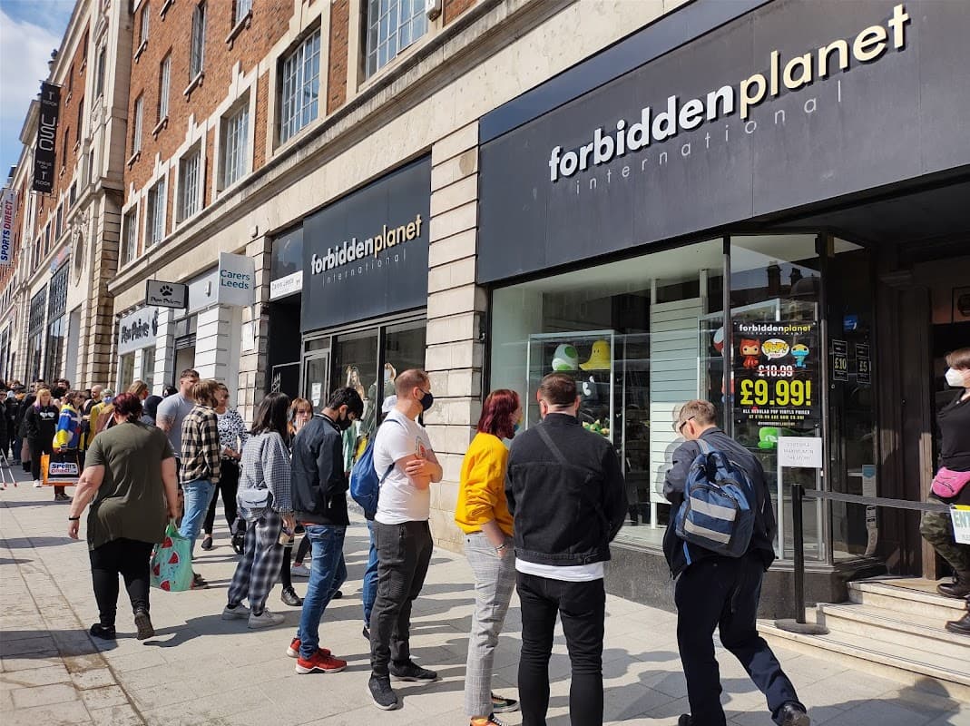 Crowd of people waiting outside Forbidden Planet International bookshop in Leeds, Yorkshire, with storefront signage visible.