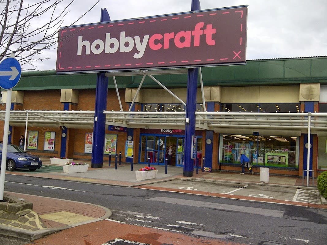 Large "Hobbycraft" sign on a retail building with glass entrance, planters, and parking area in Leeds, Yorkshire.