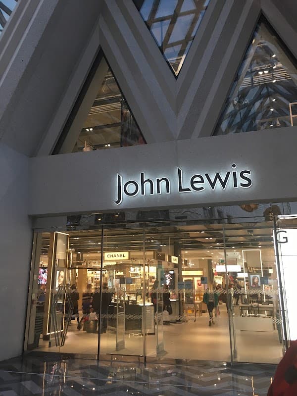 Entrance to John Lewis & Partners, featuring large glass doors and a modern architectural design, with store displays visible inside.