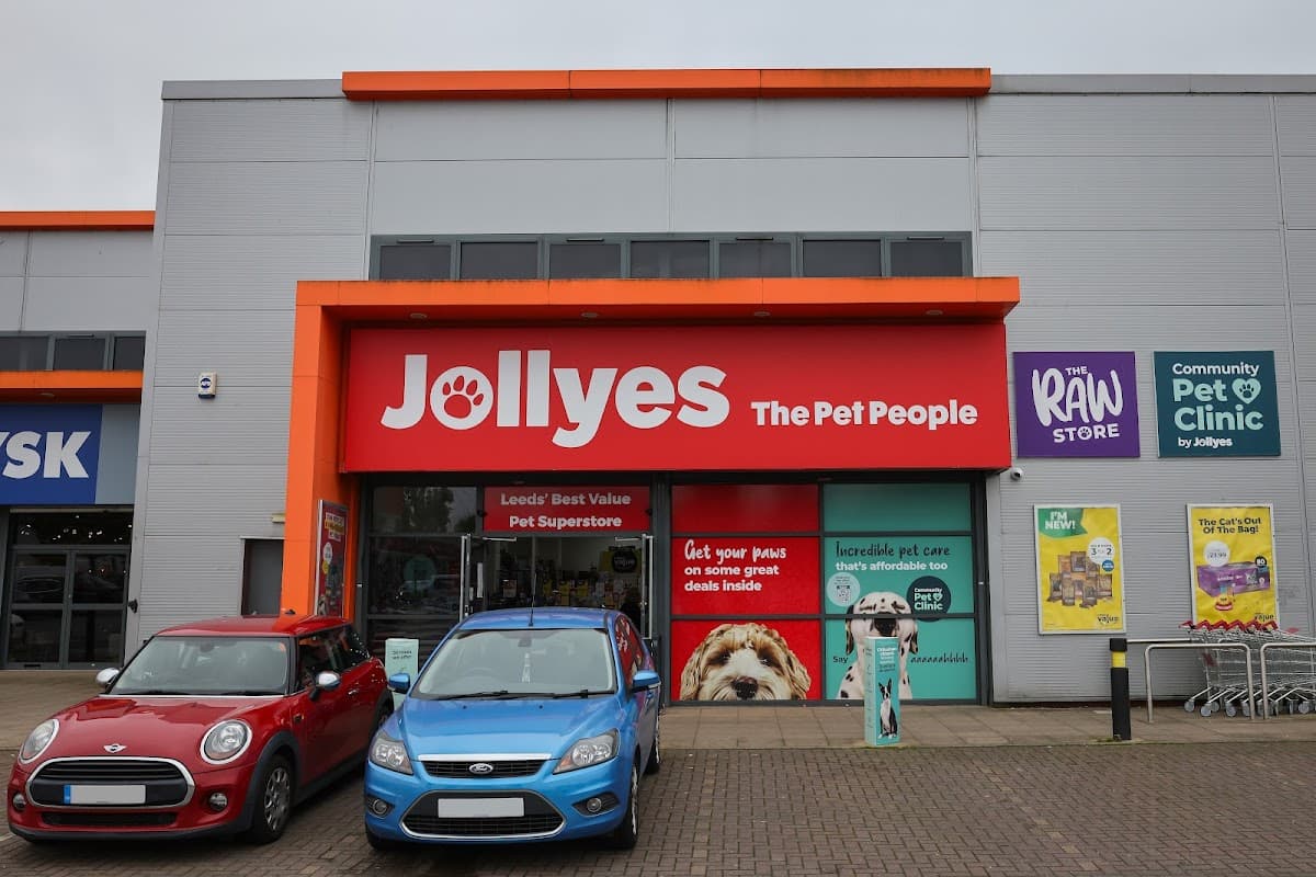 Bright storefront of Jollyes - The Pet People, featuring colorful signage and parked cars in front.