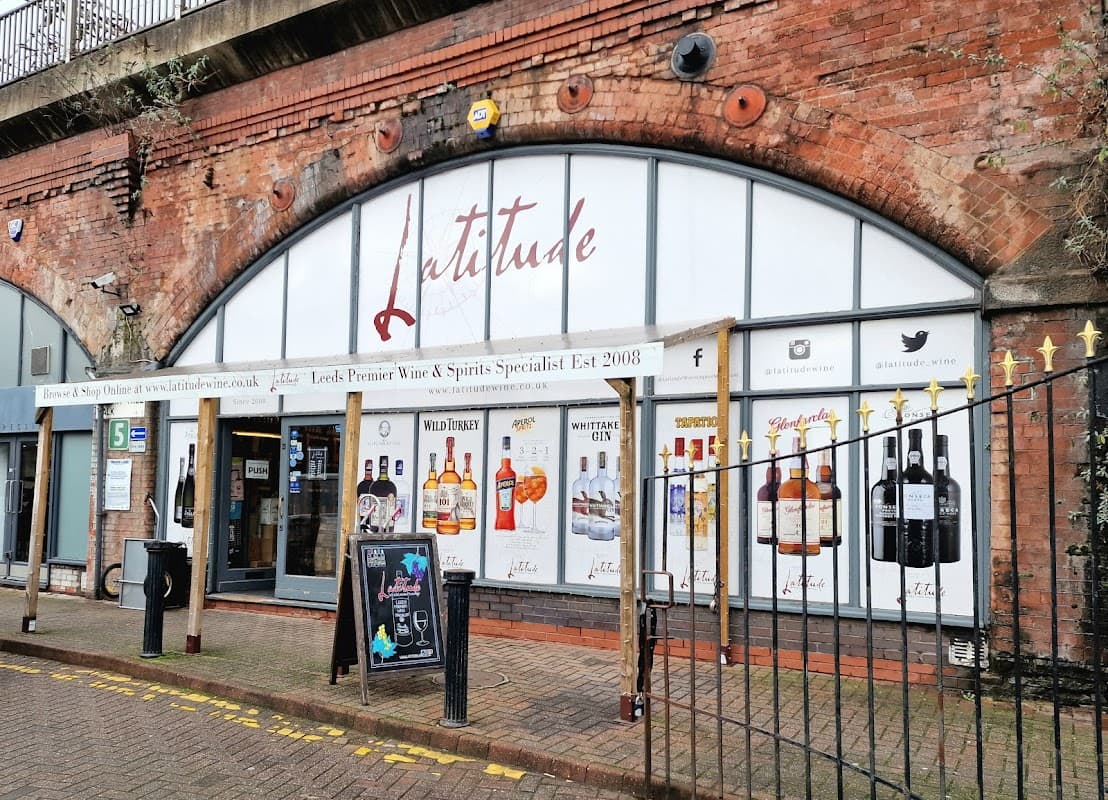Latitude Wine & Liquor Merchant storefront with large windows displaying various liquor brands and a brick archway.