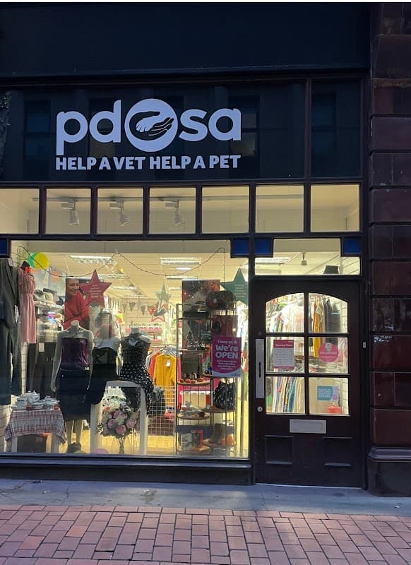 PDSA Charity Shop storefront with colorful signage, clothing displays, and a welcoming entrance.