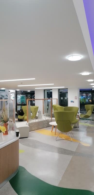 Bright, modern interior with green seating, colorful flooring, and large windows in a multi-storey car park.