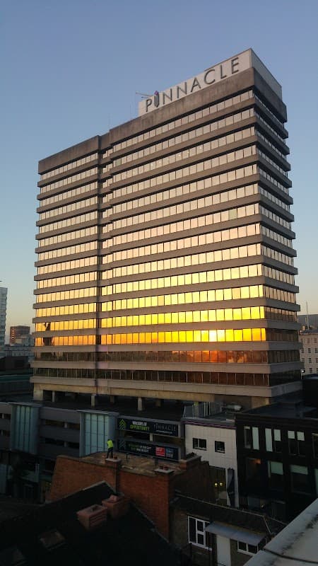 The Pinnacle building reflects a sunset, towering over surrounding structures in Leeds, Yorkshire.