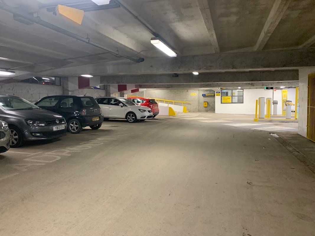 Multi-storey car park interior with parked cars, yellow barriers, and a payment kiosk in Leeds, Yorkshire.