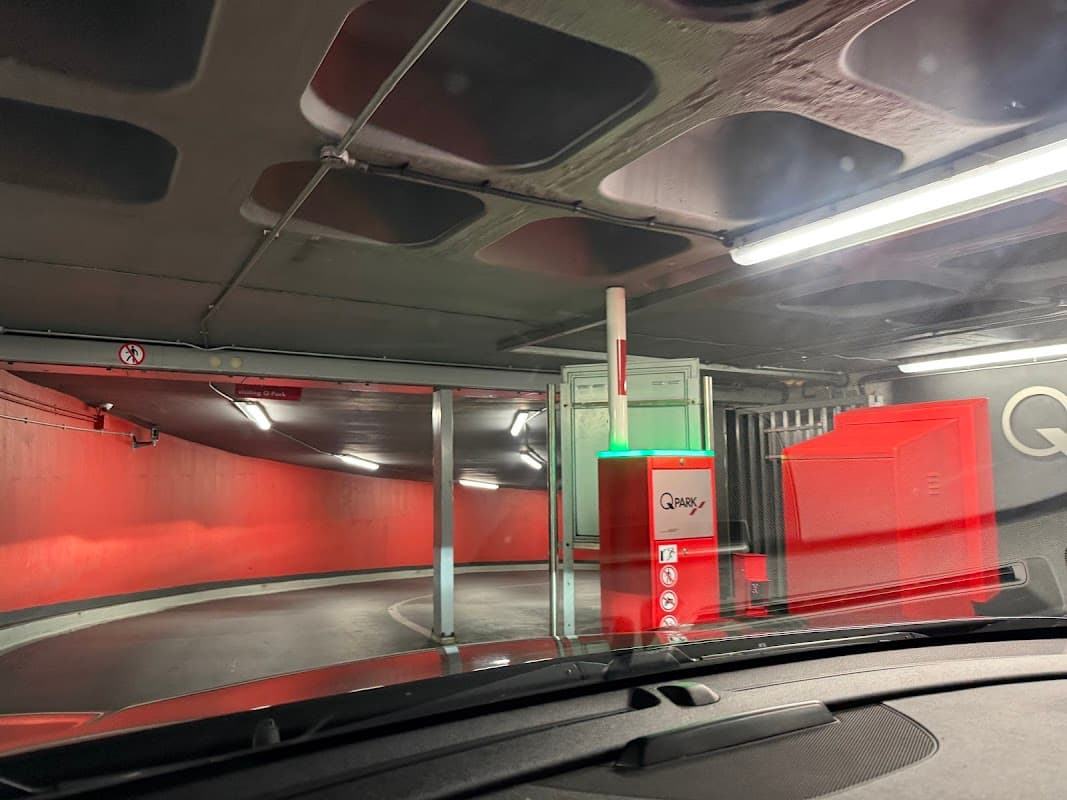 Interior of Q-Park Albion Street with a red wall, parking barrier, and illuminated signage in a multi-storey car park.