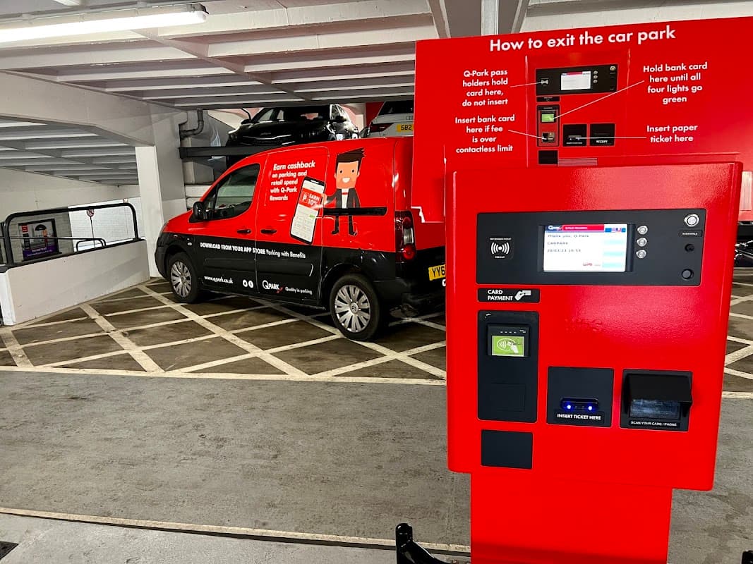 Pay & Display machine with instructions, parked vehicle, and marked parking spaces in Q-Park St Johns Centre, Leeds.