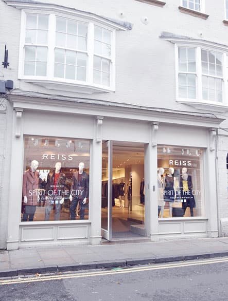 Clothes shop REISS in Leeds with mannequins showcasing stylish outfits in large front windows.
