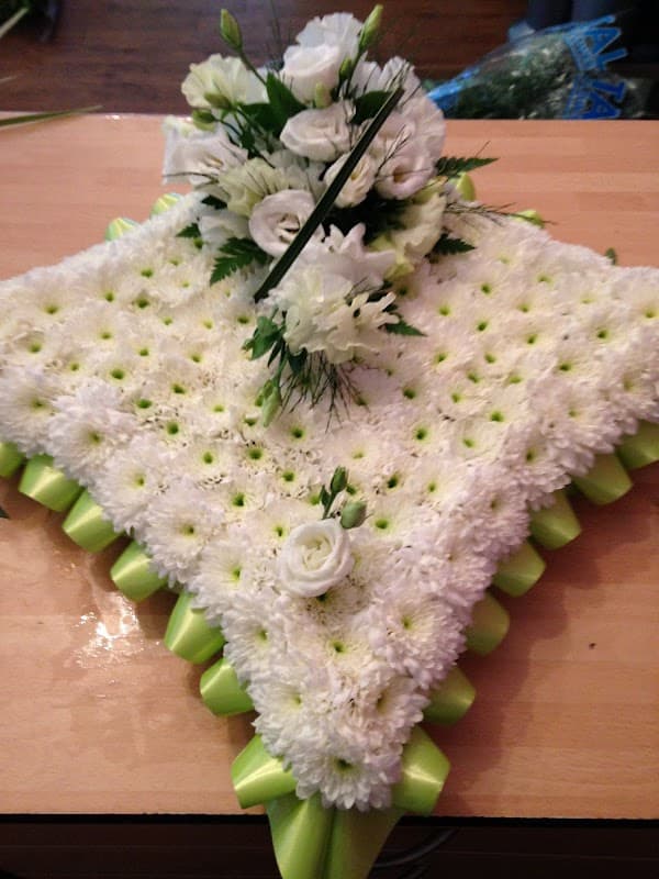 A floral arrangement featuring white flowers and green accents, artfully arranged on a textured base.