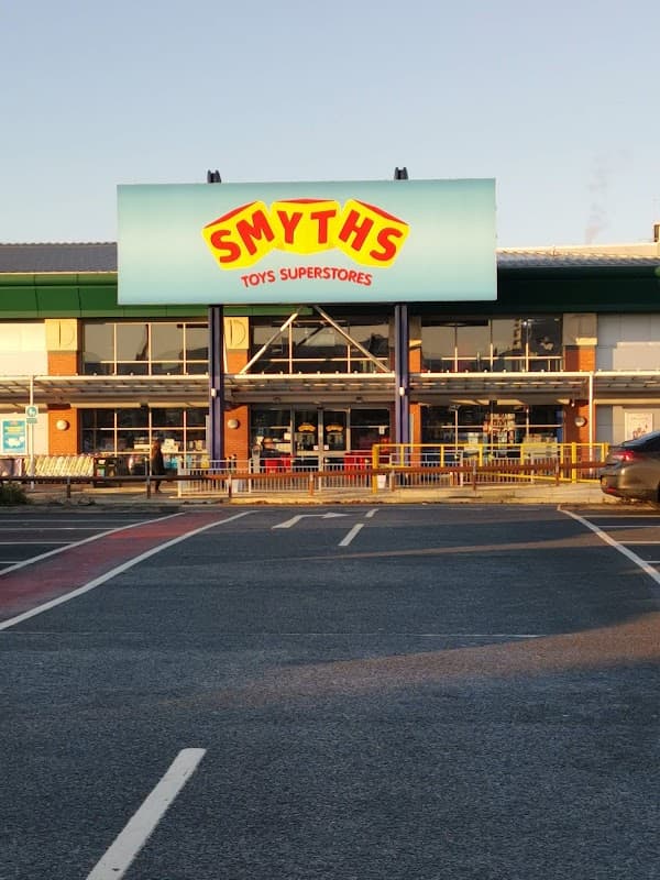 Smyths Toys Superstores storefront with bright signage, large windows, and a clear blue sky above.