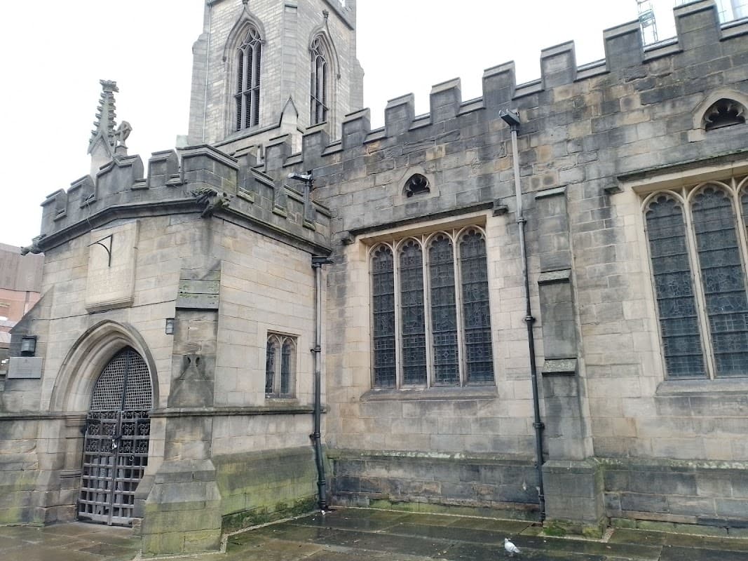Historic stone church with a tall tower, intricate windows, and a gated entrance in Leeds, Yorkshire.