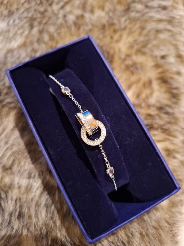 Elegant bracelet with a sparkling charm displayed in a dark blue velvet box on a textured fur background.