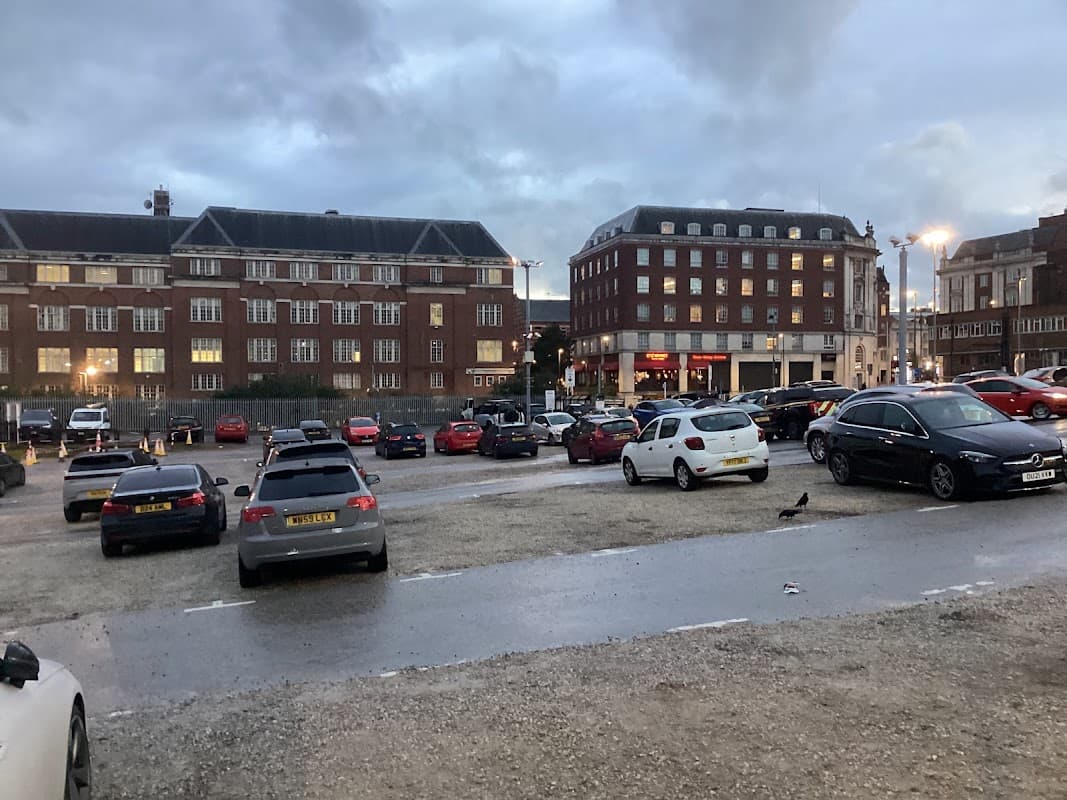 Pay & Display car park with various parked cars, buildings in the background, and a cloudy evening sky in Leeds.