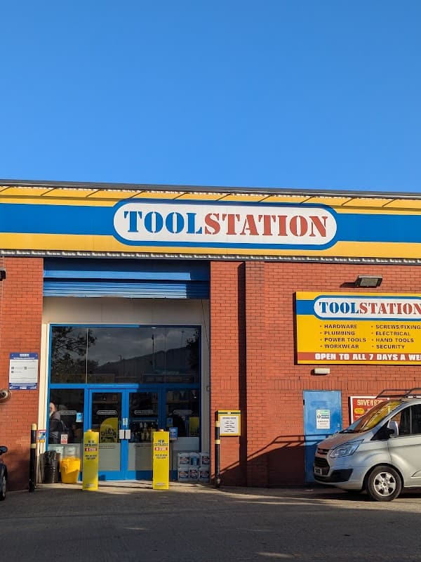Bright blue sky above a red brick building with a large "TOOLSTATION" sign and yellow storefront details.