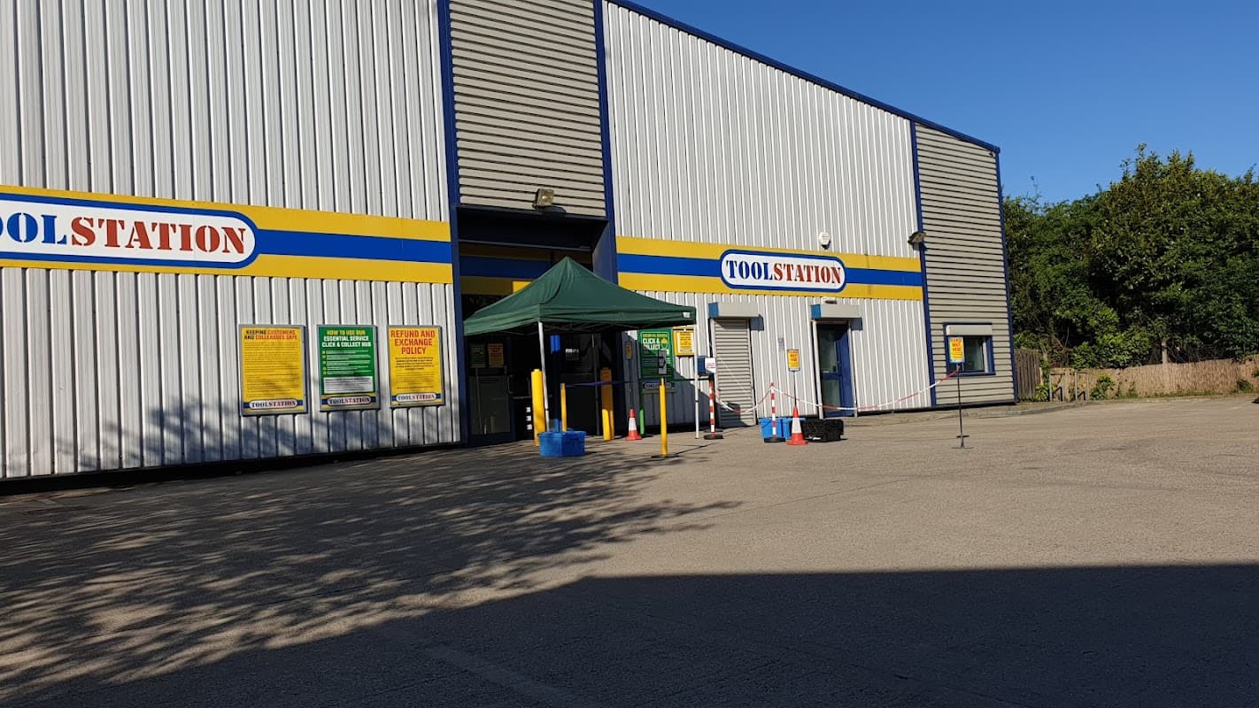 Exterior of Toolstation Leeds with a green canopy, safety barriers, and signage on a clear day.