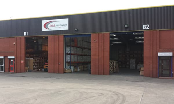 Total Hardware Ltd warehouse in Leeds, featuring large open bays and stacked pallets, with a trade counter entrance.