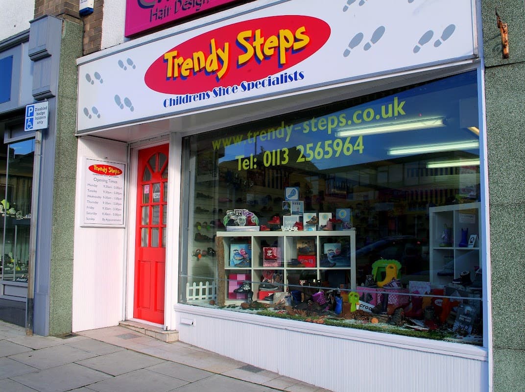 Bright storefront of Trendy Steps shoe shop, featuring children's shoes and colorful displays, with a red door and signage.