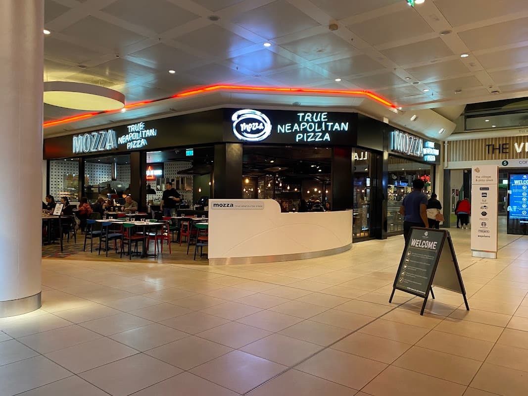 Mazza restaurant sign, indoor seating area with tables, and vibrant lighting in the White Rose Shopping Centre.