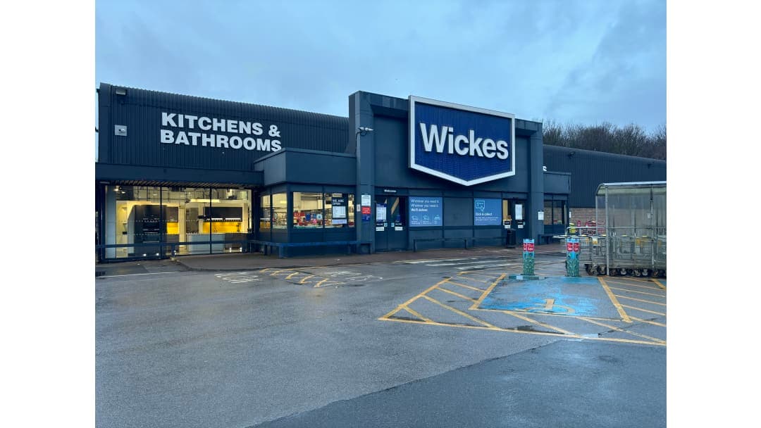 Wickes store exterior featuring signage for kitchens and bathrooms, with parking spaces in front.