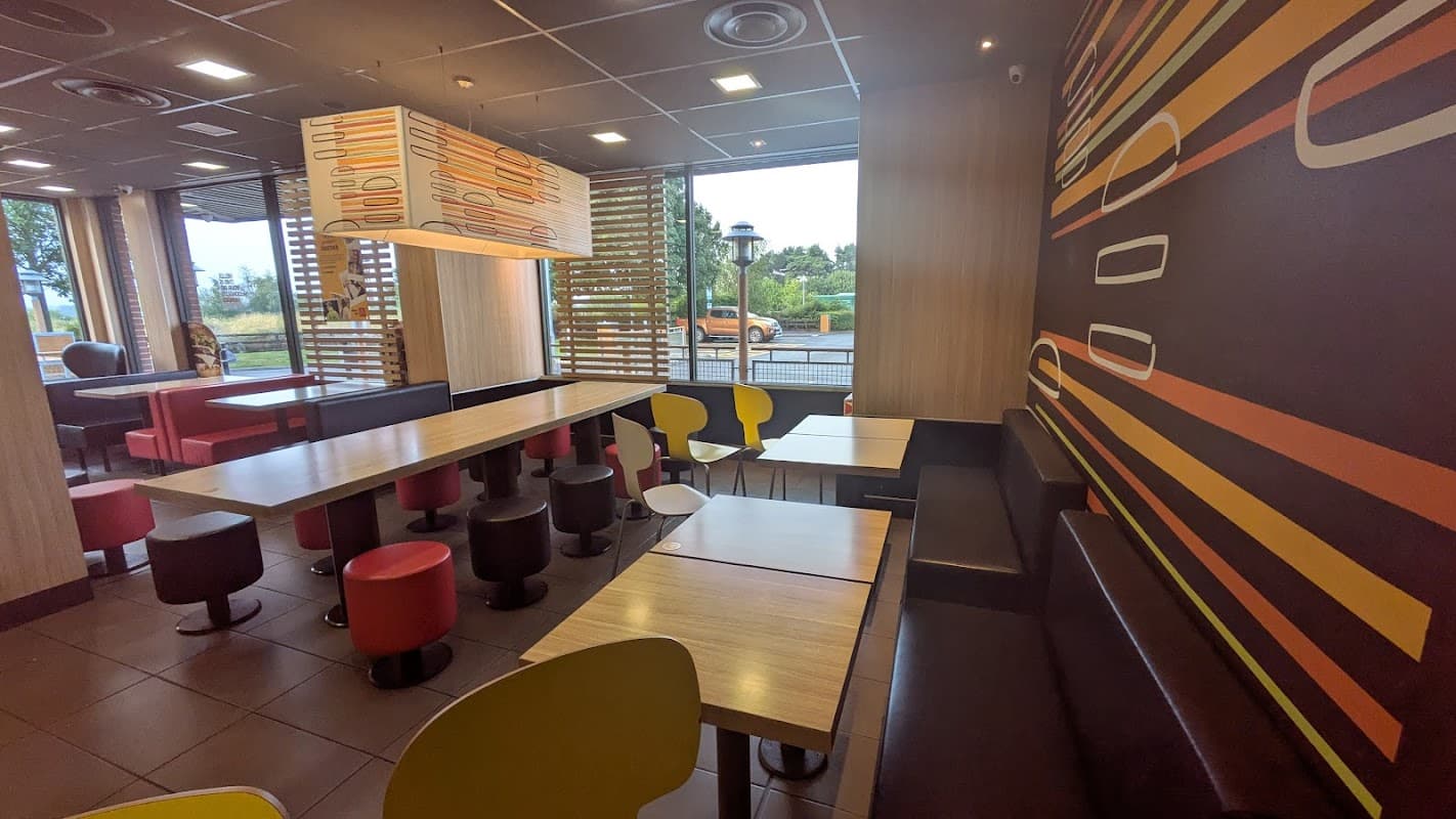 Modern cafe interior with colorful seating, wooden tables, and large windows showcasing the outdoor view.