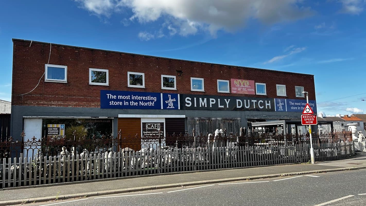 Simply Cafe exterior with a brick facade, signage, and a white picket fence under a clear blue sky.