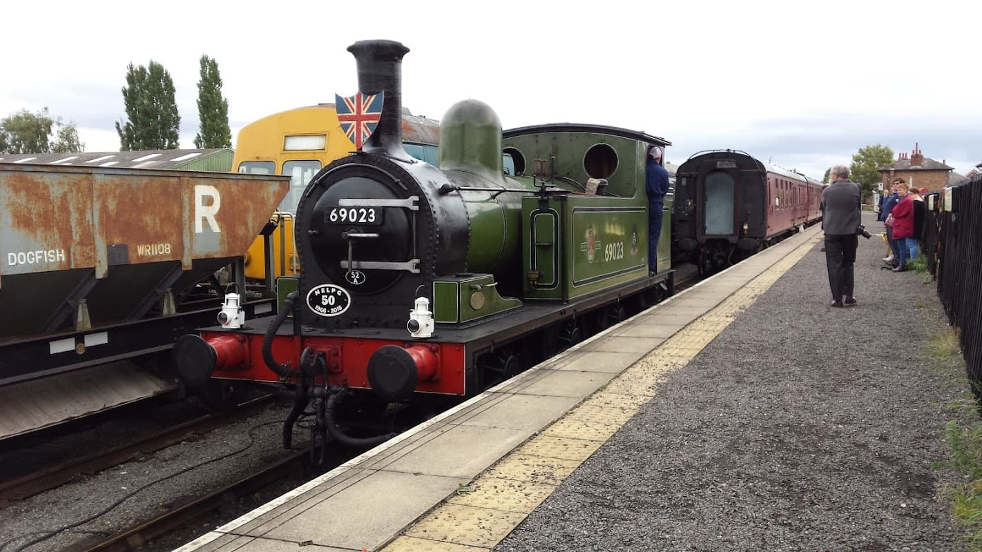 Steam locomotive 69023 at Wensleydale Railway station, with vintage carriages and passengers on the platform.