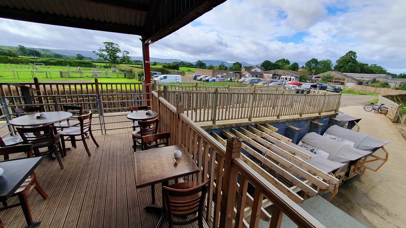 Fletchers Farm Coffee Shop features outdoor seating, wooden decking, and scenic views of fields and nearby parking.