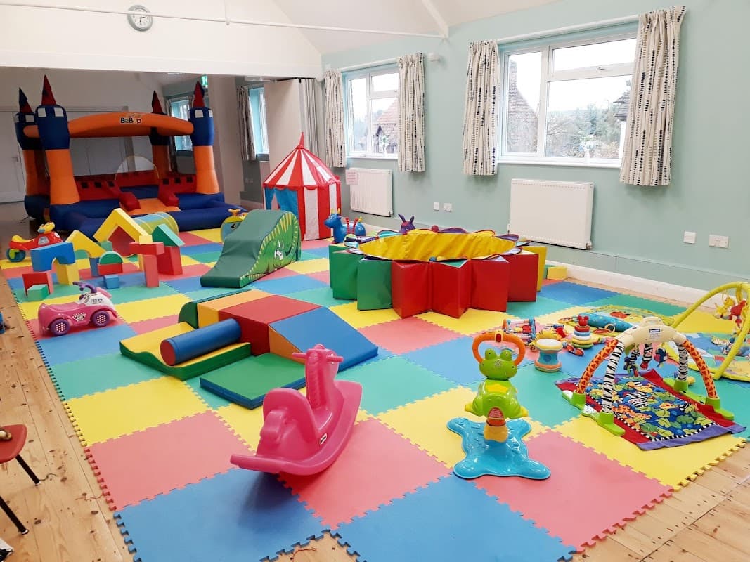 Brightly colored play area with a bouncy castle, soft toys, and various childrenβs play equipment on foam tiles.