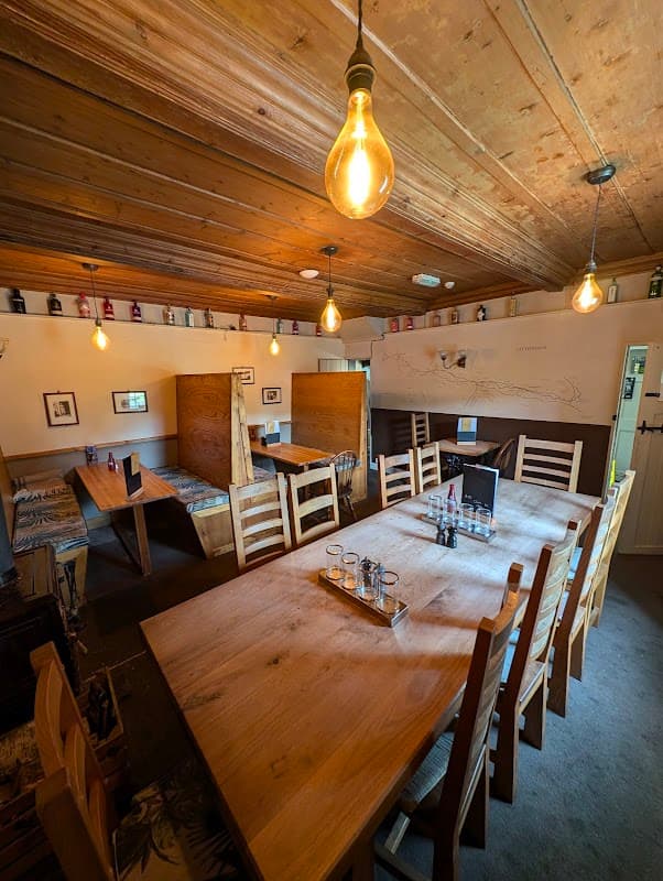 Cozy dining area with wooden tables, chairs, warm lighting, and rustic decor in The Queens Arms, Litton.