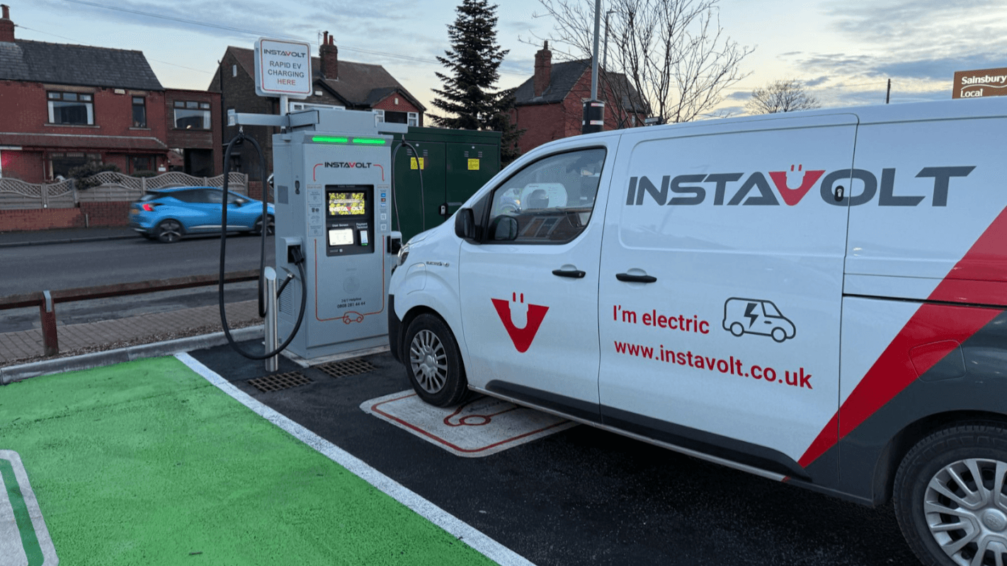 InstaVolt charging station with a van parked at the charger, surrounded by residential buildings and a green parking area.