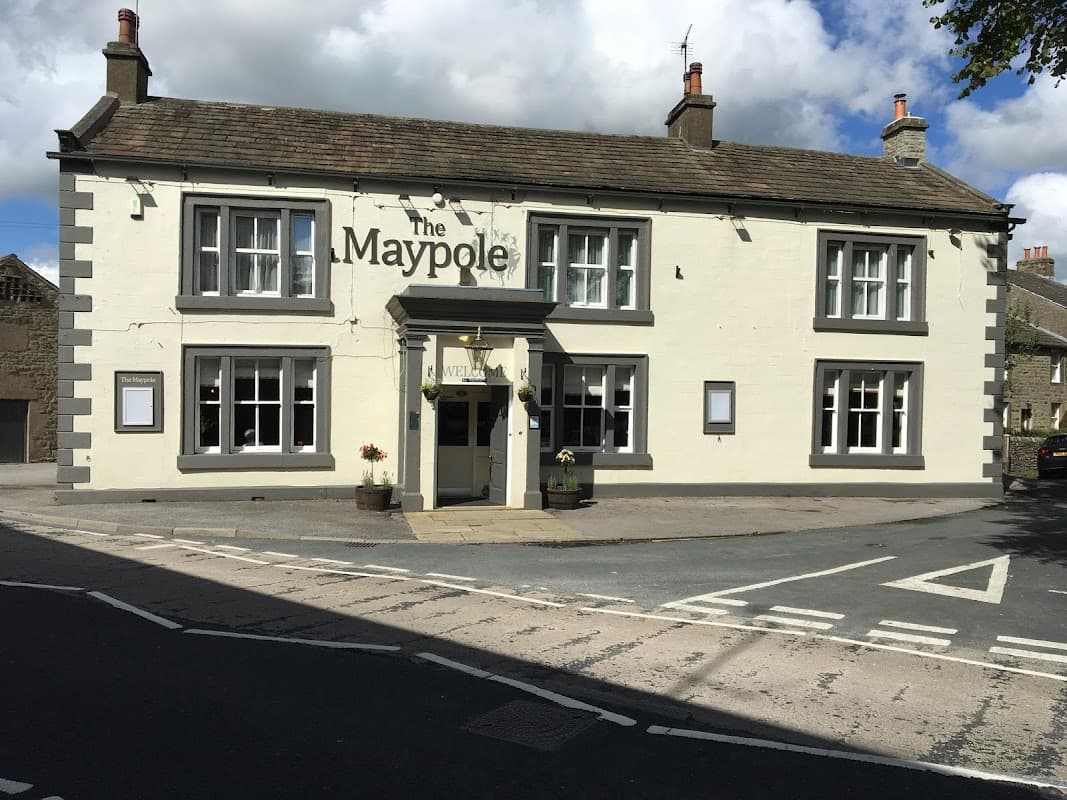 The Maypole Inn, a charming pub with a white and grey facade, situated at a street corner in Long Preston, Yorkshire.