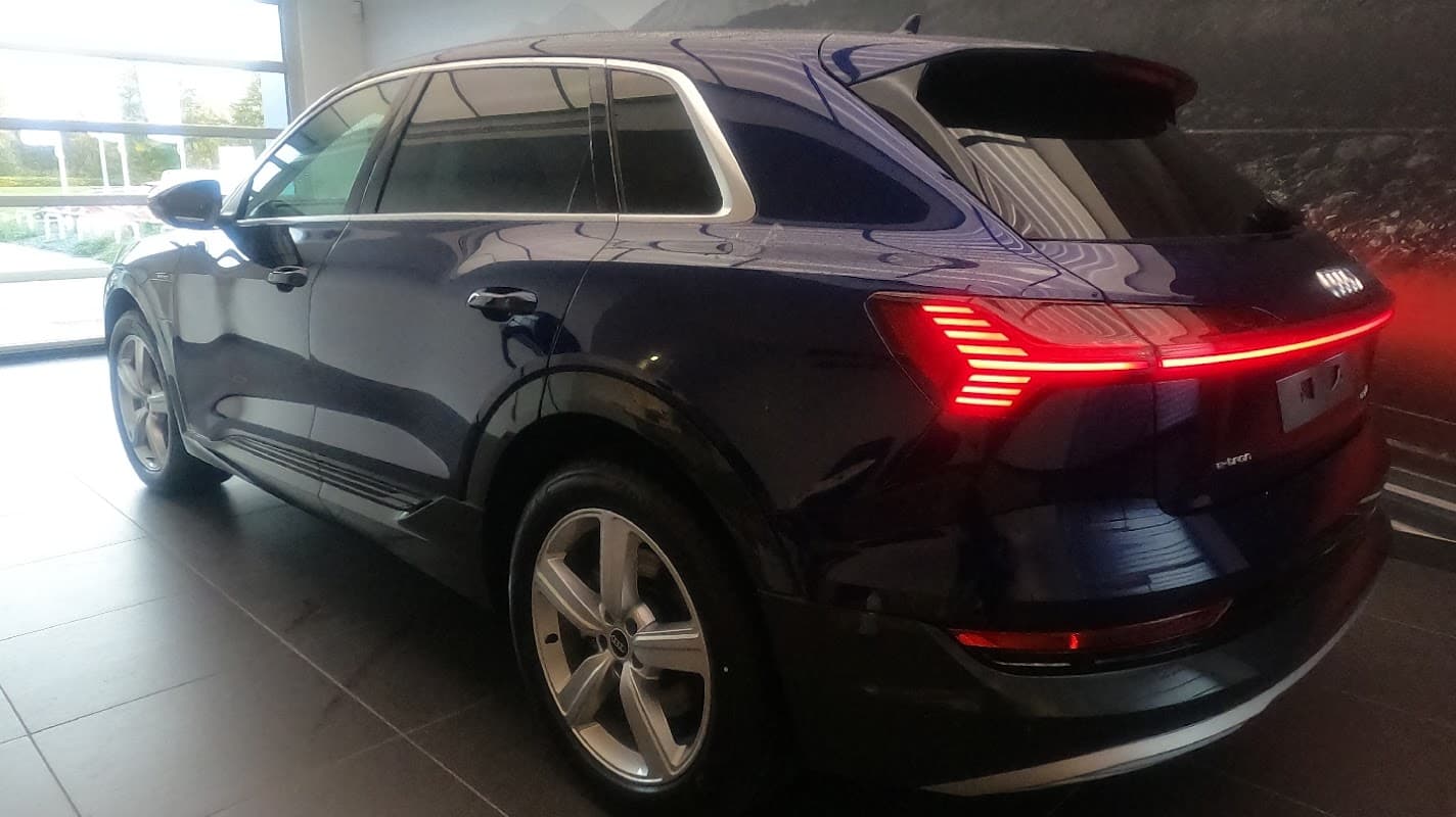 Blue SUV parked inside a modern showroom with sleek lighting and a dark background.