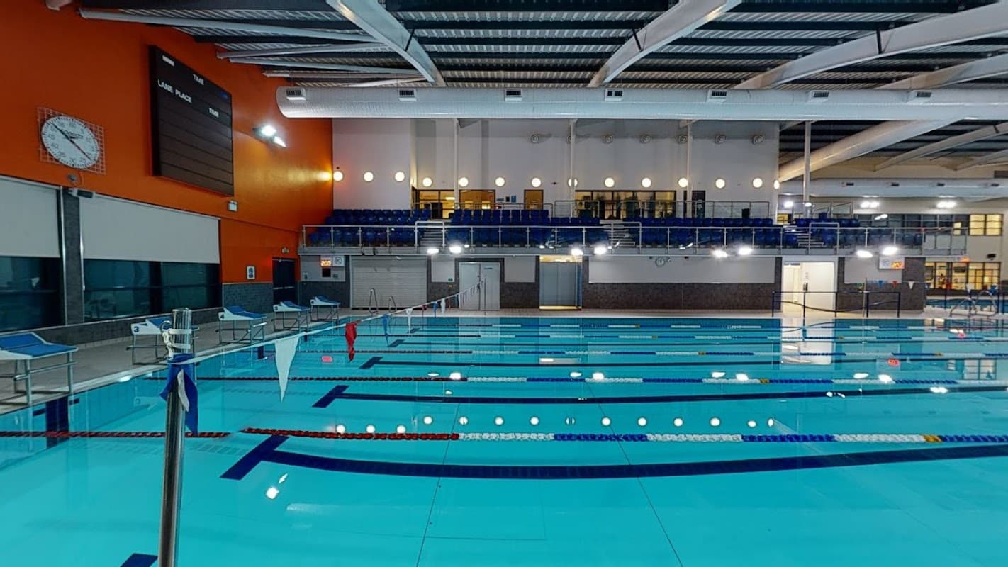 Indoor swimming pool with clear blue water, lane dividers, and seating area in a modern leisure center.