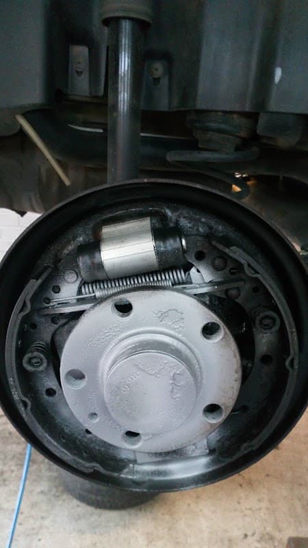 Close-up of a car brake drum assembly showing the brake shoes, spring, and cylinder components.