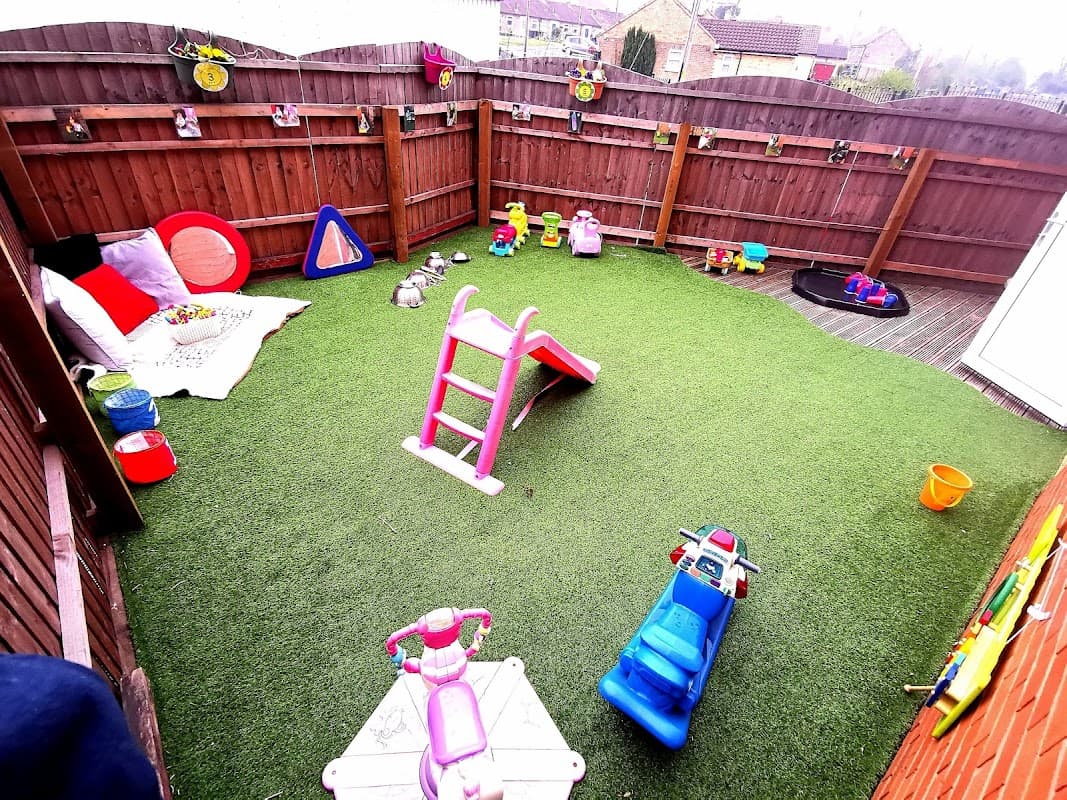 Colorful play area with artificial grass, toys, slides, and climbing equipment for young children at Once Upon a Time Nursery.