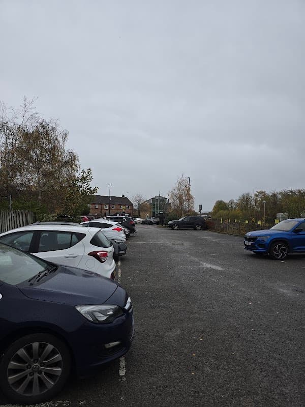 Car park in Malton, Yorkshire, with several parked cars and a cloudy sky in the background.