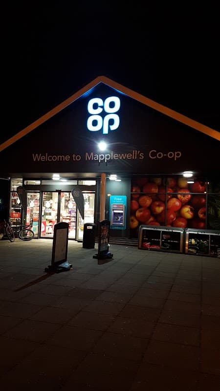 Co-op Food store in Mapplewell, Yorkshire, featuring a bright sign and apple-themed mural, illuminated at night.