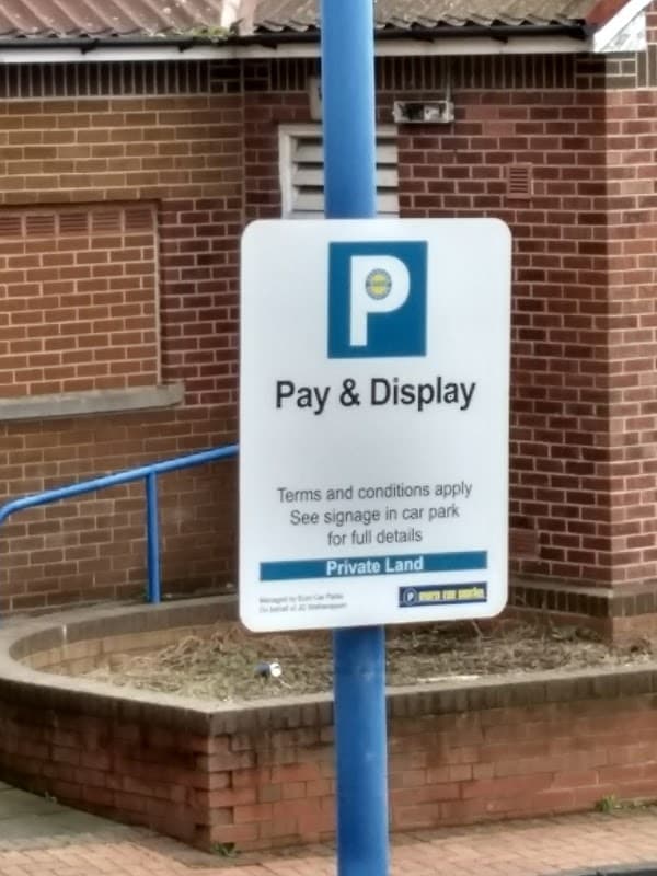 Sign for "Pay & Display" parking with terms and conditions, set against a brick wall in Montague Car Park, Mexborough.