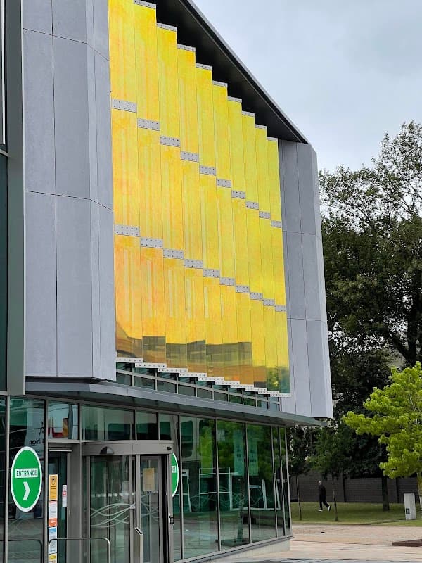 Teesside Uni parking entrance with a modern facade featuring yellow panels and green signage.