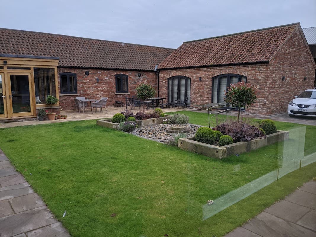 Charming hotel courtyard with landscaped garden, stone pathways, and modern seating areas.