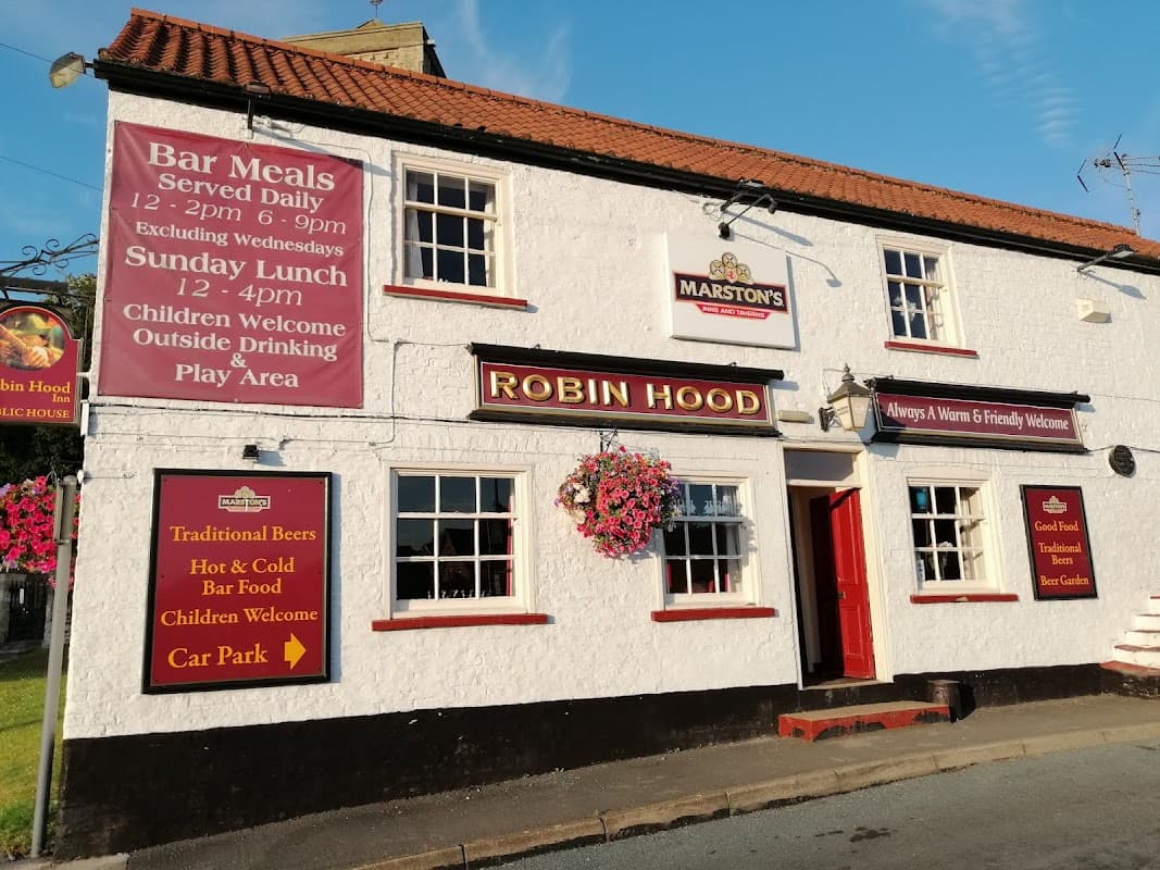 The Robin Hood Inn, a white building with red accents, featuring signs for bar meals, children's welcome, and a car park.