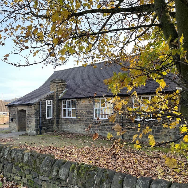 Stone building with a sloped roof surrounded by autumn leaves and a low stone wall in Millhouse Green, Yorkshire.